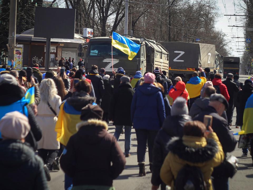 Ukrainian protesters walk toward Russian army trucks.