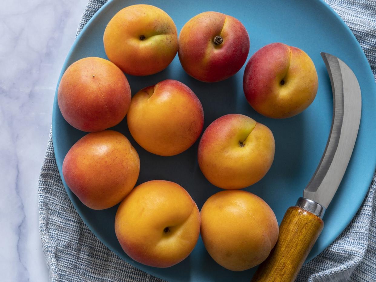 peaches in a white marble background over a blue dish