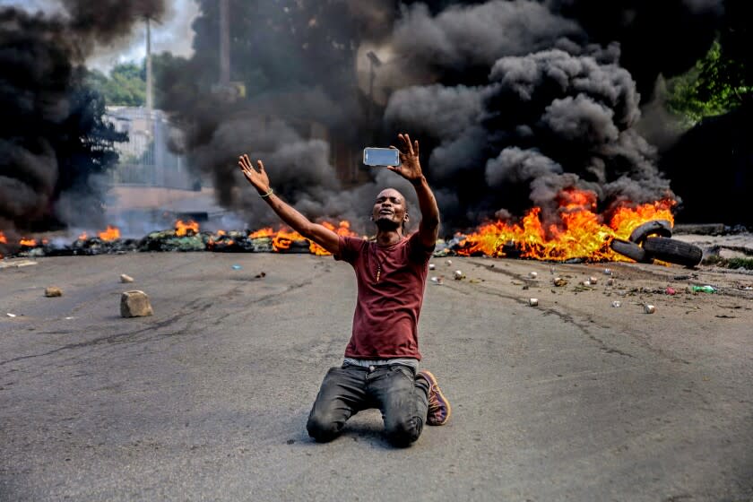 A man films himself in front of tires on fire during a general strike in Port-au-Prince on October 18, 2021.