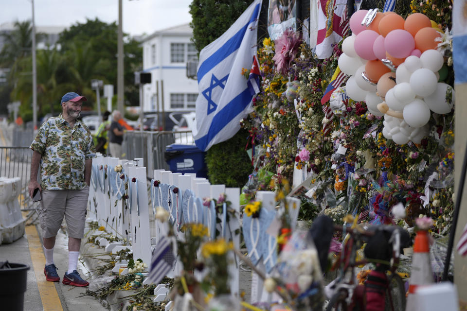 Peter Martin, of New York, who was in Miami visiting his brother, pays his respects at a makeshift memorial for the victims of the Champlain Towers South building collapse, on Monday, July 12, 2021, in Surfside, Fla. (AP Photo/Rebecca Blackwell)