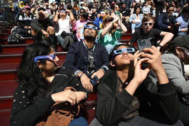 <p>Erik Pendzich/Shutterstock </p> People wear soar glasses to watch the Eclipse in Times Square on April 08, 2024 in New York City.