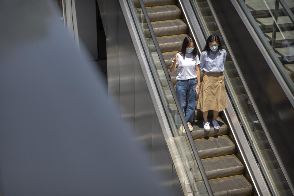 People wear face masks to protect against the coronavirus as they ride an escalator at a retail and office complex in Beijing, Friday, June 5, 2020. China on Friday reported five new confirmed coronavirus cases, all of them brought by Chinese citizens from outside the country. (AP Photo/Mark Schiefelbein)