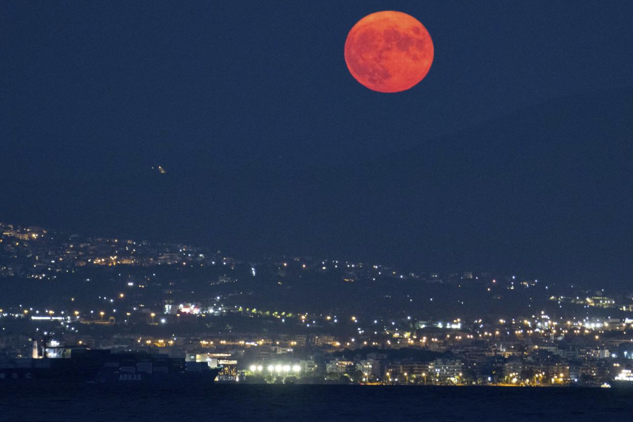 The August Sturgeon full moon rises behind the Hortiatis mountain and Thessaloniki city over the sea, skywatchers call it Blue Moon. The lunar moonlight is reflected on the water surface while it rises in warm red color near Kalochori town with the famous Lagoon and Axios Delta National Park. The country offers free cultural events at sites, a tradition for Greece with Museums Across the country open at night while a number of free cultural events will take place on August 22, at Greece's archaeological sites and museums to mark the full moon celebrations, earth's natural satellite and the beginning of the summer ending. Kalohori, Thessaloniki, Greece on August 22, 2021