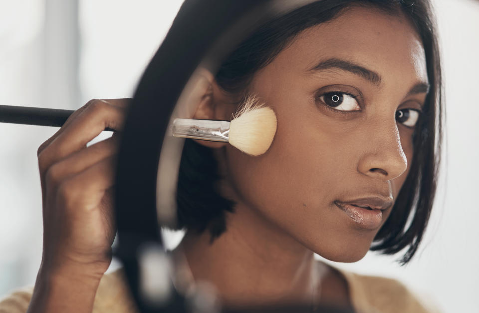 Shot of a young woman applying makeup while filming a beauty tutorial at home