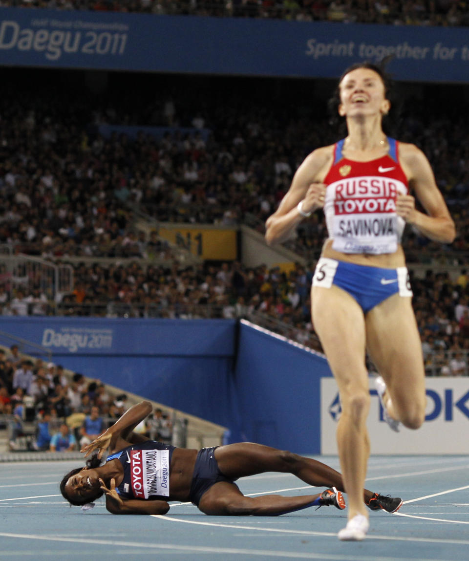 FILE - In this Sept. 4, 2011, file photo, Alysia Montano, of the United States, left, falls as she crosses the finish line in fourth place as Russia's Mariya Savinova, right, celebrates winning the Women's 800m final at the World Athletics Championships in Daegu, South Korea. On Monday, Sept. 30, 2019, Montano walked off the track at the World Championships in Doha, Qatar, with a pair of bronze medals that were placed around her neck several years too late. The U.S. 800-meter runner who has stood up on behalf of every athlete who has ever kept off the medals stand by a doper finally got the third-place prizes she was robbed of at two straight worlds, back in 2011 and 2013.(AP Photo/Anja Niedringhaus, File)
