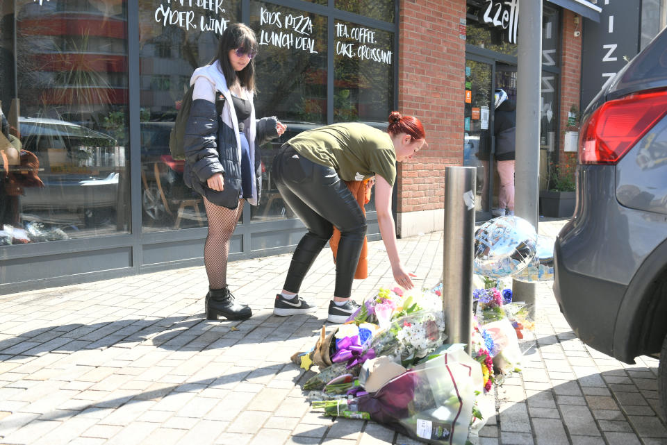 People place flowers at the scene in Barking Road, East Ham, where a 14-year-old boy was knifed to death on Friday. Picture date: Saturday April 24, 2020.