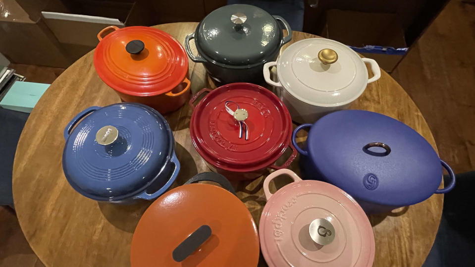 Eight Dutch ovens on a wood table