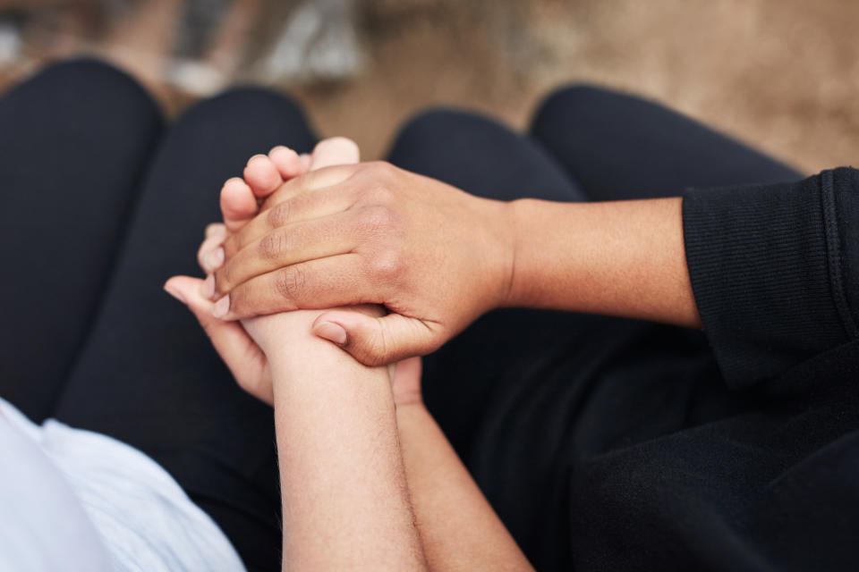 Two people hold hands as if comforting each other