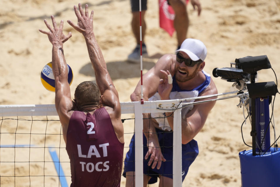 Alison Cerutti, right, of Brazil, takes a shot as Edgars Tocs, of Latvia, defends during a men's beach volleyball quarterfinal match at the 2020 Summer Olympics, Wednesday, Aug. 4, 2021, in Tokyo, Japan. (AP Photo/Petros Giannakouris)