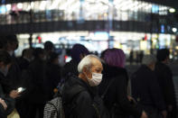 A man wearing a protective mask to help curb the spread of the coronavirus waits at a pedestrian crosswalk Wednesday, Nov. 25, 2020, in Tokyo. The Japanese capital confirmed more than 400 new coronavirus cases on Wednesday. (AP Photo/Eugene Hoshiko)