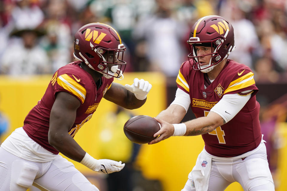 Washington Commanders quarterback Taylor Heinicke hands the ball off to running back Brian Robinson Jr., during the first half of an NFL football game against the Green Bay Packers, Sunday, Oct. 23, 2022, in Landover, Md. (AP Photo/Patrick Semansky)