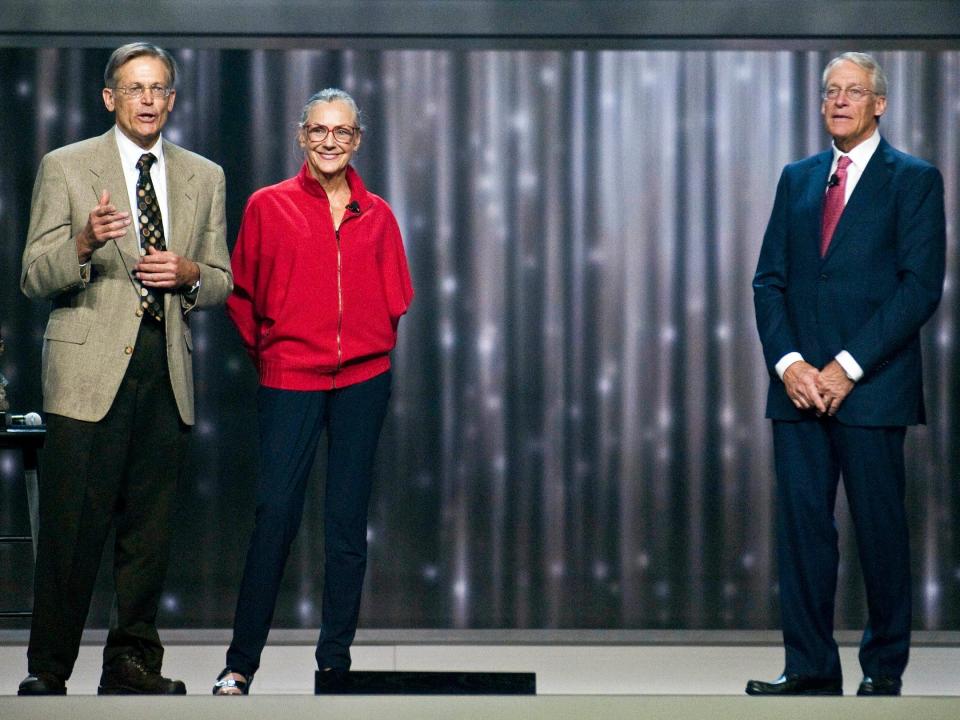 Jim Walton, Alice Walton, and Robson Walton stand on stage during Walmart event