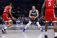 Dallas Mavericks guard Luka Doncic (77) attempts a three-point shot as New Orleans Pelicans guard Trey Murphy III (25) and forward Herbert Jones (5) defend during the second half of an NBA basketball game, Thursday, Feb. 2, 2023, in Dallas. Doncic would leave the game shortly afterwards with a right heel contusion. (AP Photo/Brandon Wade)