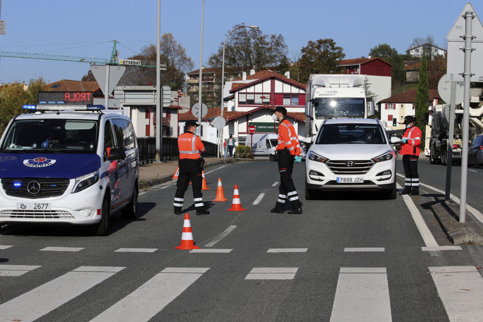 FILE - In this Spain, Friday, Oct. 30, 2020 file photo, Basque Ertzaintza police officers control cars at the French-Spanish border in Behobia, Spain. The European Union's executive body proposed Monday Jan. 25, 2021, that the bloc's 27 nations impose more travel restrictions to counter the worrying spread of new coronavirus variants but make sure to keep goods and workers moving across EU borders. (AP Photo/Bob Edme, File)