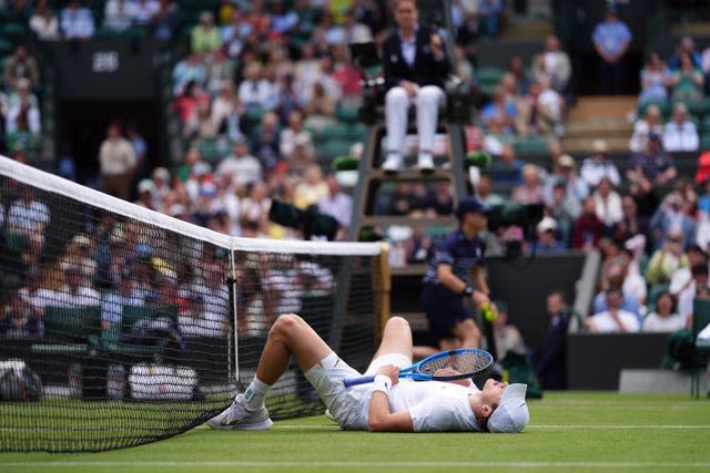 Jack Draper lies on the floor with his legs in the net