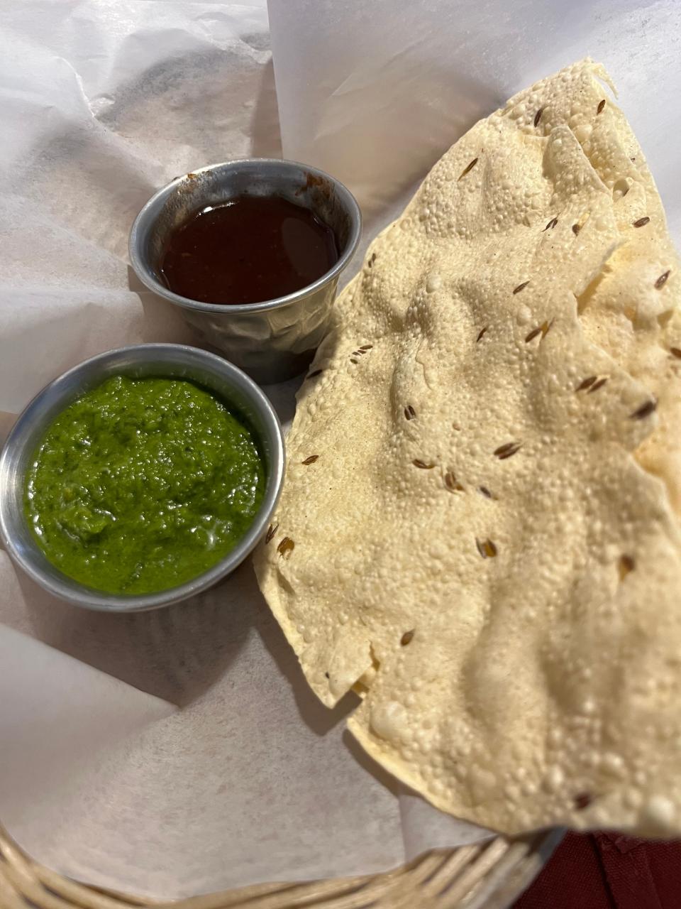 Papadam, a crispy lentil wafer, is complimentary at The Spice Delight, served with mint and tamarind chutneys.