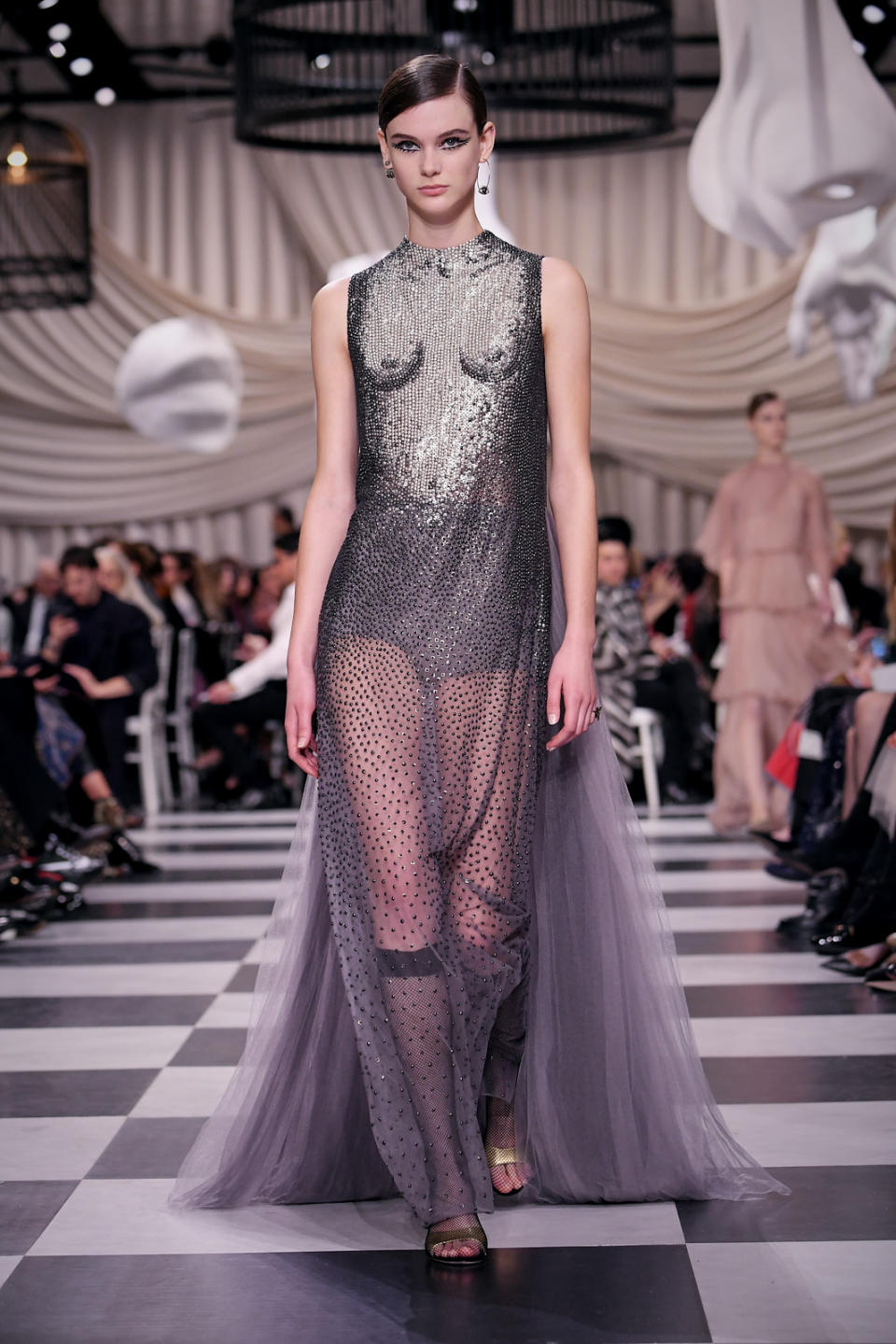 <p>A model wears a silver shimmery dress depicting a woman’s unclothed torso and chest with a long sheer tulle bottom from the Dior Haute Couture SS18 collection. (Photo: Getty) </p>