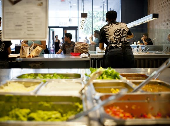 Inside a Chipotle Mexican Grill restaurant with the food line and workers.