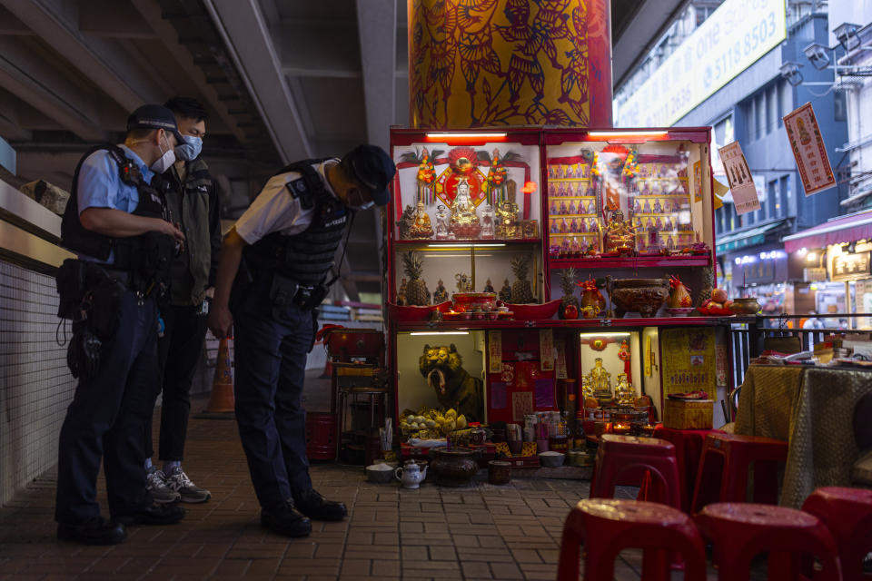 Police officers and a plainclothes police officer inspect a "villain hitting" booth during a routine patrol under the Canal Road Flyover in Hong Kong, on Sunday, March 5, 2023. (AP Photo/Louise Delmotte)