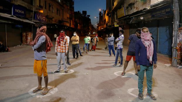 People stand apart in a line to receive free food being distributed on a street in New Delhi.
