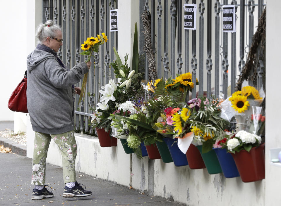 A woman prepares to lay flowers outside the Al Noor mosque in Christchurch, New Zealand, Sunday, March 15, 2020. A national memorial in New Zealand to commemorate the 51 people who were killed when a gunman attacked two mosques one year ago has been canceled due to fears over the new coronavirus. (AP Photo/Mark Baker)