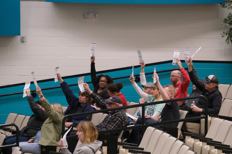 Voters raise their preference cards to help the precinct chair calculate total voters at North Valleys High School during the Nevada Democratic presidential caucuses in Reno