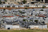 Syrian refugees sit outside their tents near the gathering point where other refugees prepare to back home to Syria as a part of a voluntary return, in the eastern Lebanese border town of Arsal, Tuesday, May 14, 2024. Hundreds of Syrians refugees left a remote northeastern Lebanese town back to Syria in a convoy, amid a surge in anti-refugee sentiment in the small, crisis-hit country. Lebanese officials for years has urged the international community to resettle the refugees in other countries or help them return to Syria. (AP Photo/Hussein Malla)