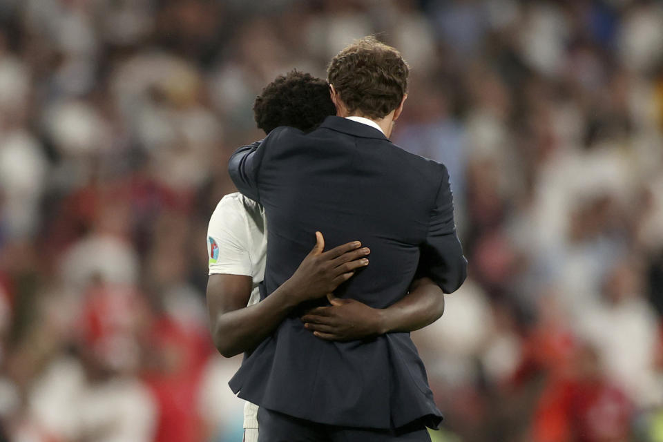 England's manager Gareth Southgate embraces Bukayo Saka after he failed to score a penalty during a penalty shootout after extra time during of the Euro 2020 soccer championship final match between England and Italy at Wembley stadium in London, Sunday, July 11, 2021. (Carl Recine/Pool Photo via AP)