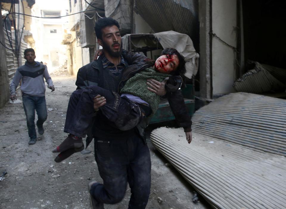 Mohammed Abu Anas runs with an injured boy in the besieged eastern Ghouta town of Hamouriyeh near Damascus, Syria, on 21 February 2018: REUTERS