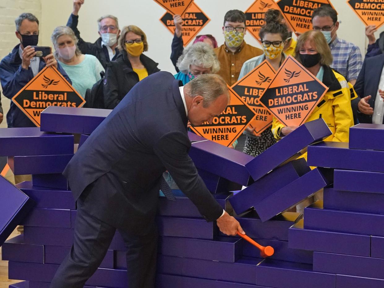 Liberal Democrat leader Sir Ed Davey knocks down blue wall made of plastic bricks at victory rally after Chesham and Amersham by-election (Steve Parsons/PA)