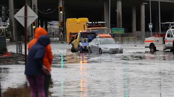 PHOTO: People look on as a tow truck pulls a car out of a flooded intersection, Jan. 4, 2023, in Mill Valley, Calif. (Justin Sullivan/Getty Images)
