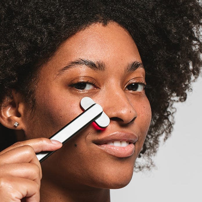 A model using a Solawave red light device on her face