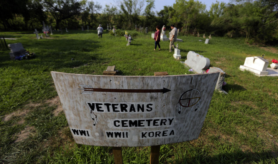 In this Wednesday May 1, 2019 photo, family members walk around the the Eli Jackson Cemetery in San Juan, Texas. While the government has agreed to exempt some wildlife preserves and heritage properties from border wall construction, plenty of others remain under threat. (AP Photo/Eric Gay)