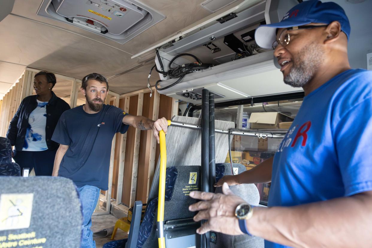 Robert Ford, right, founder of local nonprofit Forever R Children, talks with Kamper City service foreman Chris Lehman about the conversion of a Metro RTA into a mobile shower facility to serve the community.
