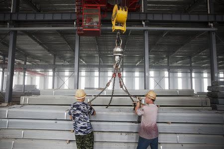 Workers wrap metal chains around steel bars to be transported at warehouse of the Baifeng Iron and Steel Corporation in Tangshan in China's Hebei Province August 3, 2015. REUTERS/Damir Sagolj