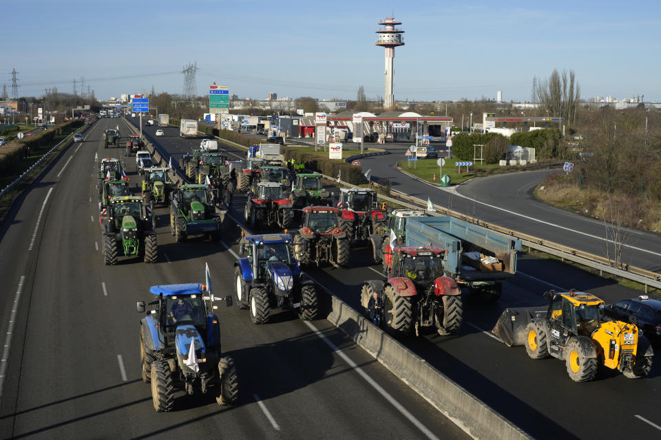 Tractors are parked on a highway in Villabe, south of Paris, Friday, Jan. 26, 2024 in Paris. Protesting farmers shut down long stretches of some of France's major motorways on Friday, using their tractors to block and slow traffic and squeeze the government ever more tightly to cede to their demands that growing and rearing food should be made easier and more lucrative. (AP Photo/Thibault Camus)