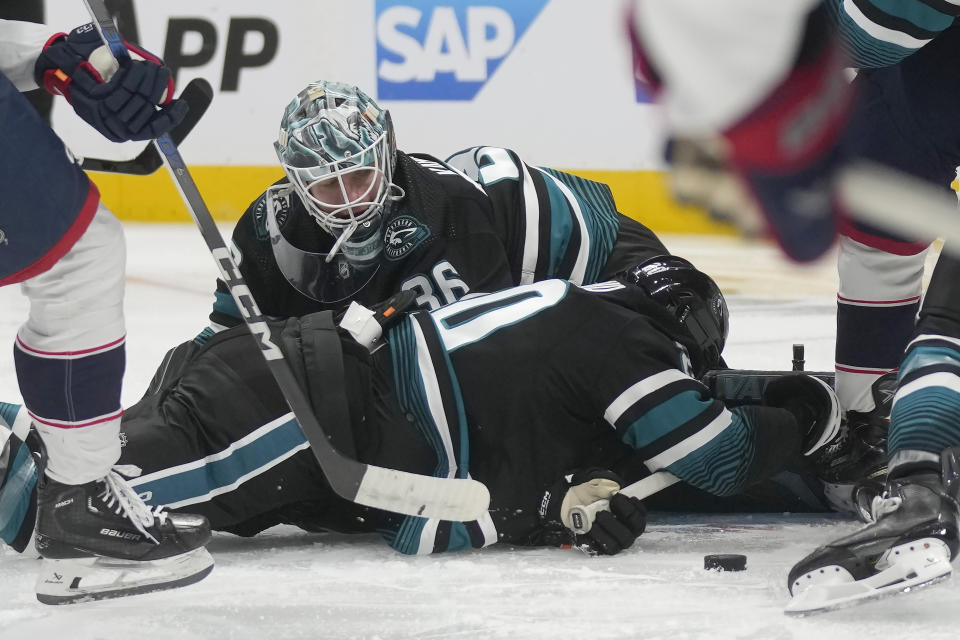 San Jose Sharks goaltender Kaapo Kahkonen, top, looks for the puck behind left wing Fabian Zetterlund during the second period of the team's NHL hockey game against the Columbus Blue Jackets in San Jose, Calif., Saturday, Feb. 17, 2024. (AP Photo/Jeff Chiu)