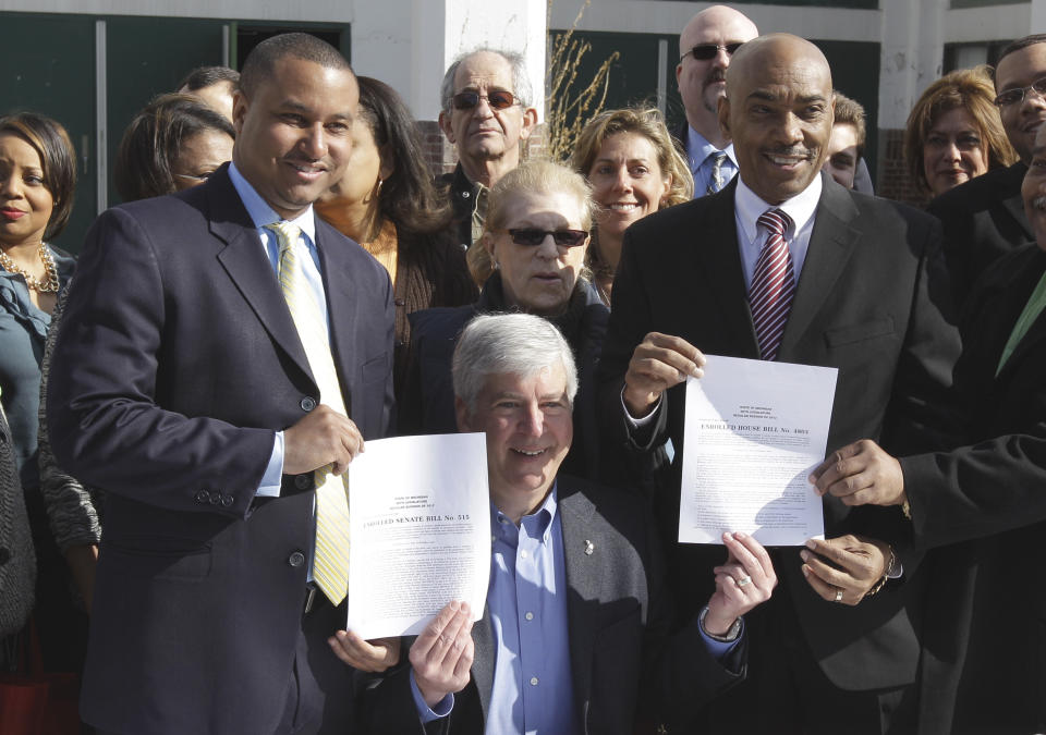 Michigan Gov. Rick Snyder, center, holds up legislation while posing with State Sen. Virgil Smith, left, and State Rep. Jimmy Womack, right, during a bill signing ceremony at the Michigan State Fairgrounds in Detroit, Monday, April 9, 2012. The legislation returns the fairgrounds in Detroit to productive use. The governor signed the two bills aimed at setting the stage for possible redevelopment of the 162-acre site. (AP Photo/Carlos Osorio)