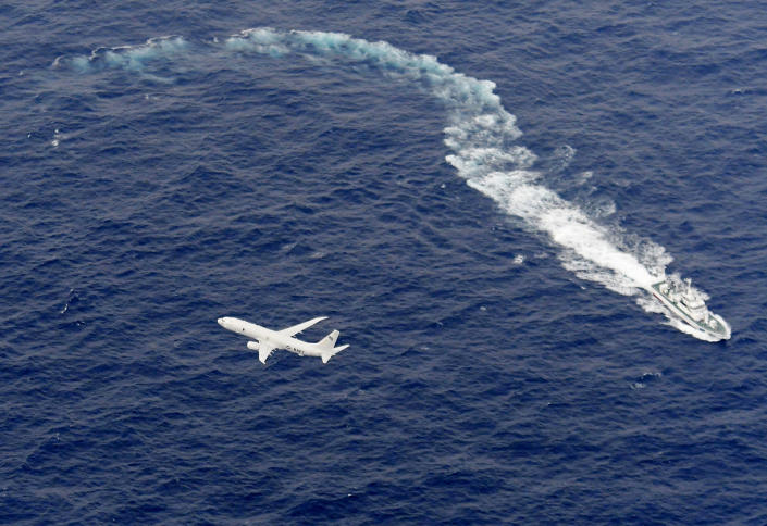 In this Dec. 6, 2018, aerial photo, Japan's Coast Guard ship, top, and U.S. military plane are seen at sea off Kochi, southwestern Japan, during the search and rescue operation for missing crew members of the U.S. Marine refueling plane and fighter jet. One of two crew members recovered after two U.S. warplanes collided and crashed off Japan's coast early Thursday is dead and five others remain missing, the U.S. military said. (Kyodo News via AP)