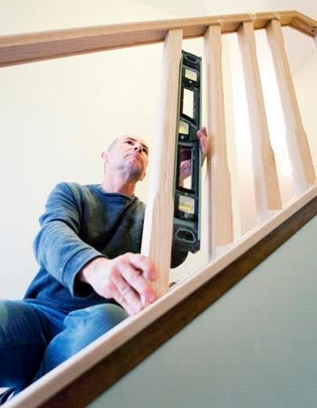 A man uses a tool during a staircase remodel.