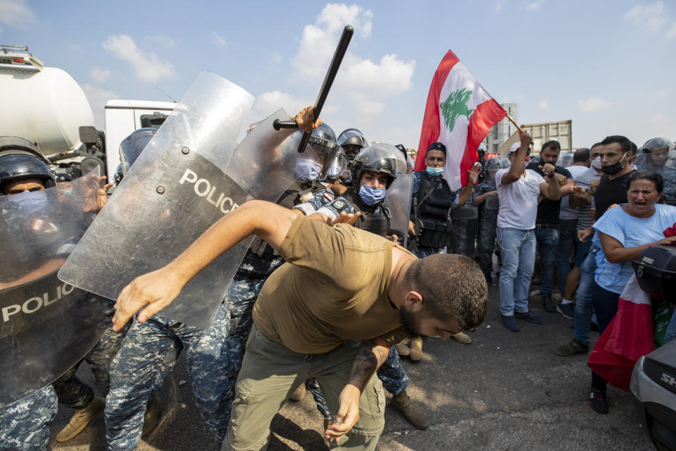 Riot police scuffle with anti-government protesters outside the Ministry of Energy and Water in Beirut, Lebanon, Tuesday, Aug. 4, 2020. Dozens of Lebanese protesters tried to storm the Ministry of Energy on Tuesday, angered by prolonged power cuts as the country grapples with a crippling economic crisis. (AP Photo/Hassan Ammar)