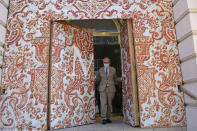 David Margulis, owner of Margulis Jewelers, emerges from a double layer of plywood doors he had installed to protect his store from protests that have dominated the city of Portland, Ore., for seven weeks, Monday, July 13, 2020. While most of the demonstrations have been peaceful, nightly violent clashes between police and protesters have divided the liberal city, paralyzed the downtown and attracted the attention of President Donald Trump, who sent federal law enforcement to the city to quell the unrest. (AP Photo/Gillian Flaccus)