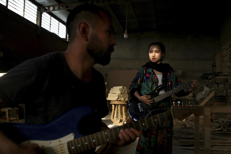 In this July 26, 2018 photo, Afghan musicians Hakim Ebrahimi, left, and Soraya Hosseini, members of the Arikayn rock band, play music at a furniture workshop on the outskirts of Tehran, Iran. Like others in Iran's vibrant arts scene, Afghan musicians must contend with hard-liners who view Western culture as corrupt and object to women performing in public. (AP Photo/Ebrahim Noroozi)