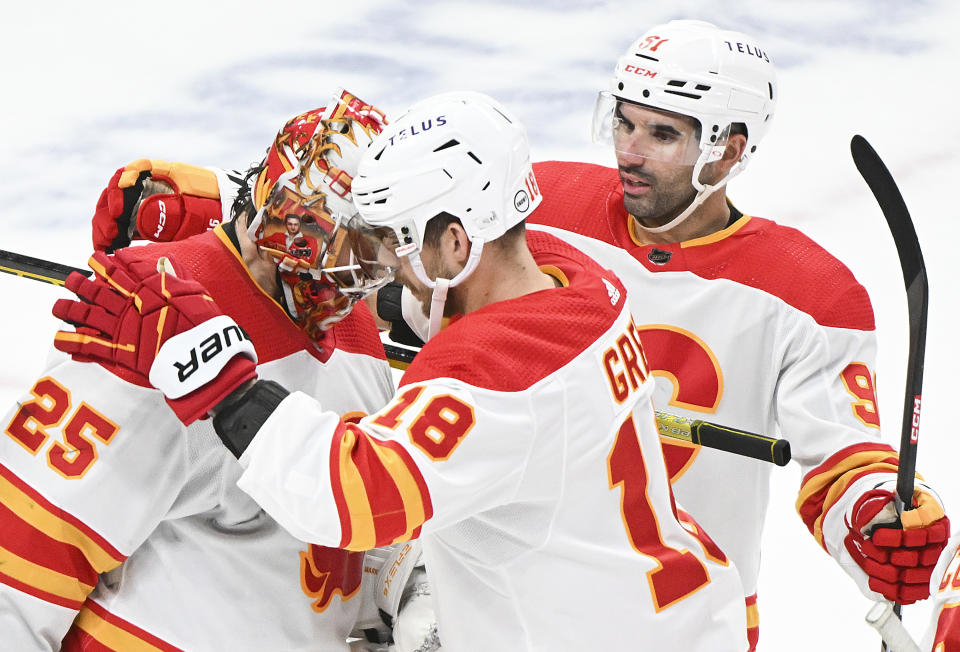 Calgary Flames goaltender Jacob Markstrom (25) celebrates with teammates Nazem Kadri, right, and A.J. Greer (18) after defeating the Montreal Canadiens in an NHL hockey game in Montreal, Quebec, Tuesday, Nov. 14, 2023. (Graham Hughes/The Canadian Press via AP)