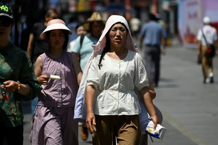 Una mujer camina por una calle de Pekín con una capucha para protegerse del calor el 11 de junio de 2024 (Wang Zhao)