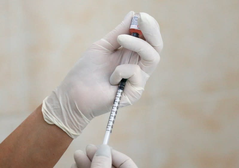 A nurse fills a syringe with a vaccine before administering an injection at a children's clinic in Kiev