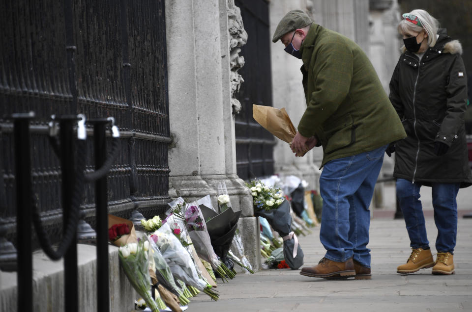 Un hombre deja un ramo de flores en la puerta del Palacio de Buckingham, en Londres, el 10 de abril de 2021, un día después de la muerte del príncipe Felipe, el marido de la reina Isabel II. (AP Foto/Alberto Pezzali)