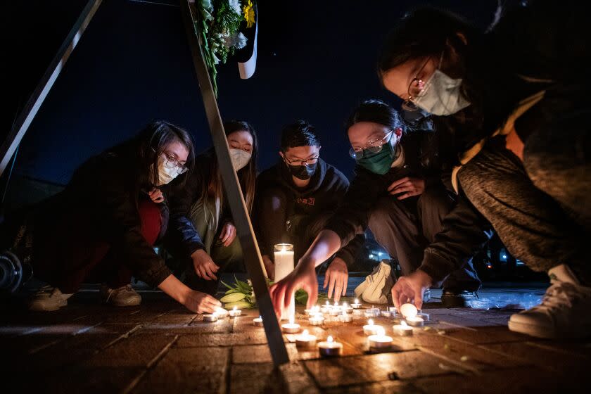 Monterey Park, CA - January 23: Community members light candles in the shape of a heart amidst a growing memorial of flowers and candles as they pay their respects during a candlelight vigil honoring the victims of the mass shooting that occurred Sunday at the Star Dance Studio that left 11 people dead and 9 others wounded at Monterey Park Community Center in Monterey Park, Monday, Jan. 23, 2023. A memorial of flowers and other mementos has been growing outside Monterey Park City Hall since Sunday. The Star Dance Studio is where Huu Can Tran, a 72 year old Asian male, is accused of shooting and killing 10 people and injuring 10 during the Monterey Park mass shooting that took place Saturday night. (Allen J. Schaben / Los Angeles Times)