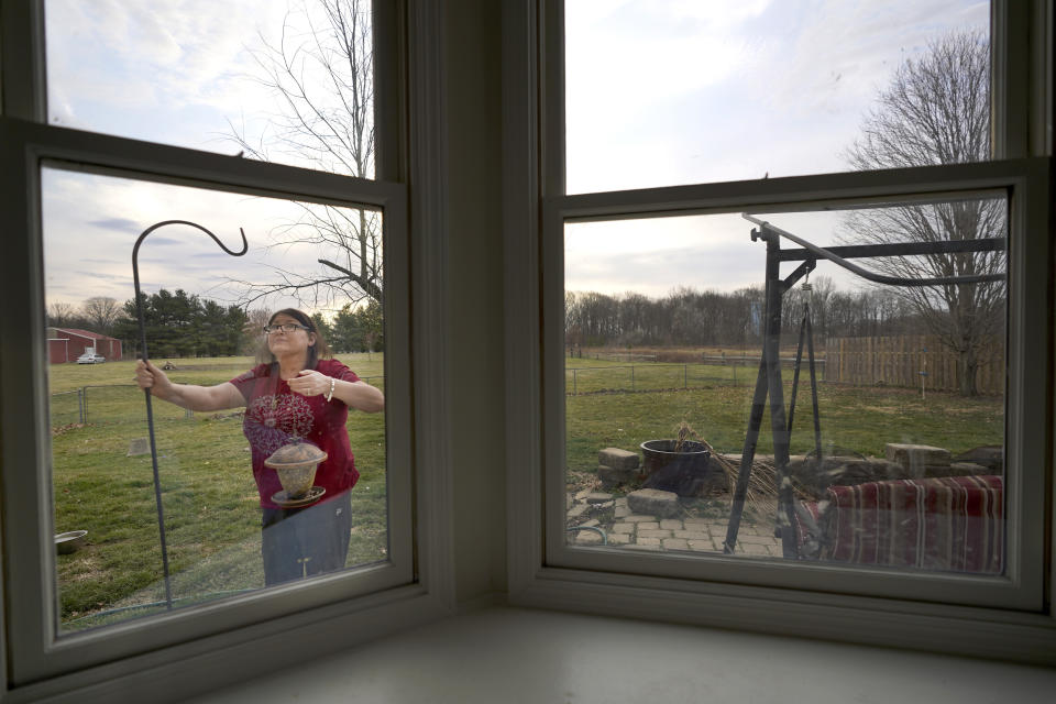 Keri Wegg refills a bird feeder outside her kitchen window in Westfield, Ind., on Tuesday, March 23, 2021. “It’s her same personality, she’s just toned down a little bit because she’s just really tired,” says a friend, Dana Downing. “She just keeps on focusing on what she can do, rather than what she can’t do.” (AP Photo/Charles Rex Arbogast)