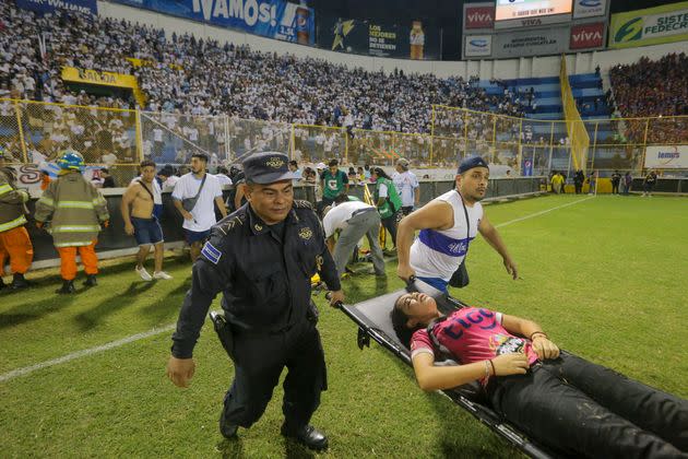 An injured fan is carried on the field of Cuscatlán Stadium in San Salvador, El Salvador, on Saturday. At least 12 people were killed and dozens more injured when stampeding fans pushed through one of the access gates at the quarterfinal soccer match between Alianza and FAS.